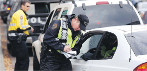 A Victoria police officer writes a ticket during a distracted-driving road check on Johnson Street.  BRUCE STOTESBURY, TIMES COLONIST 